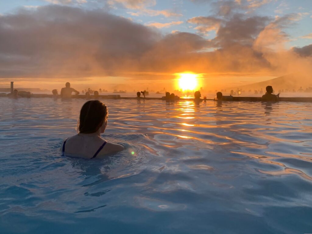 Vrouw in Myvatn Nature Baths, kijkend naar de zonsondergang, IJsland
