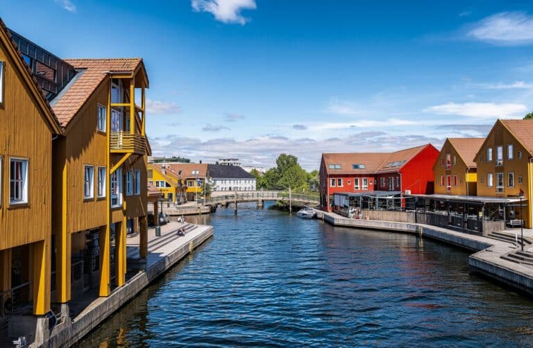 Zicht over het water en op de pier van Kristiansand met gele en rode houten winkelpanden en restaurants