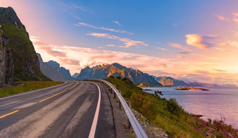 Een weg langs bergen en water tijdens zonsondergang