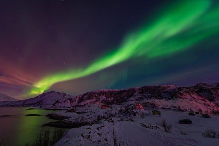 Noorderlicht in het donker boven besneeuwde bergen