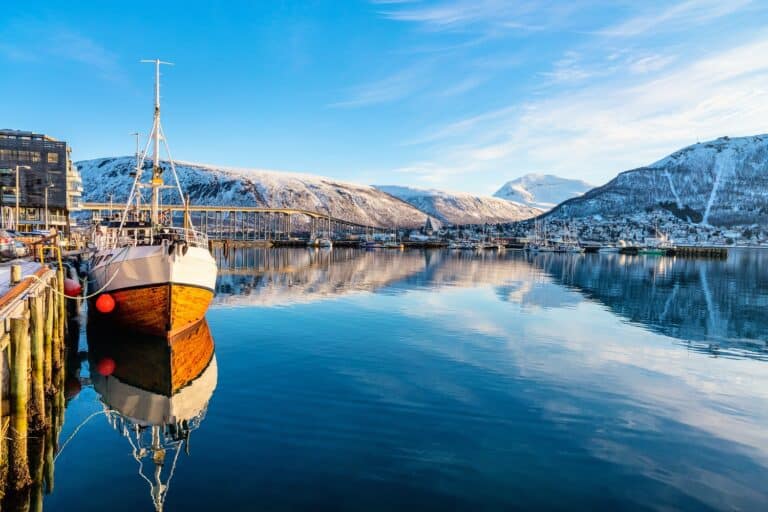 Zicht vanaf de haven in Tromsø over het water en de besneeuwde bergen