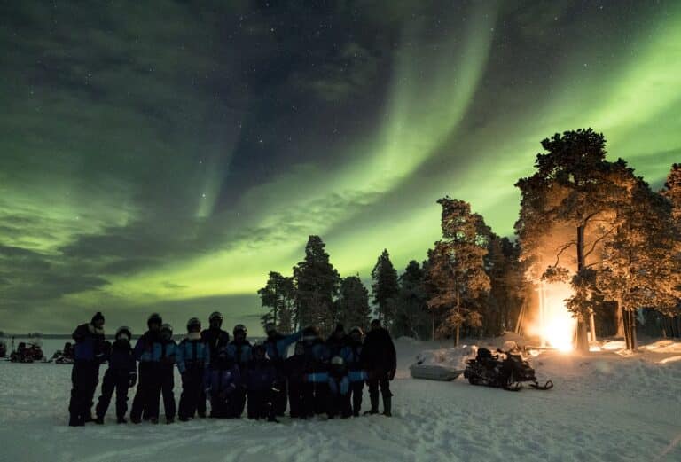 Groep mensen bekijkt het noorderlicht tijdens een aurora camp