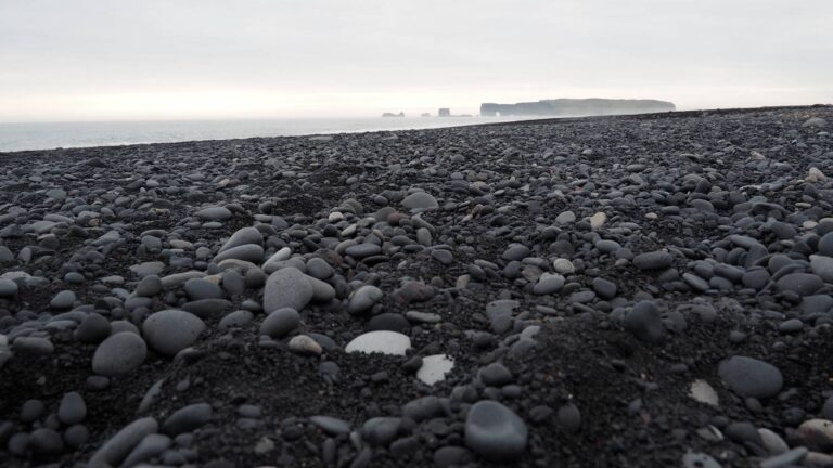 Zwart strand Reynisfjara, met op de achtergrond de rotsen van Dyrholaey