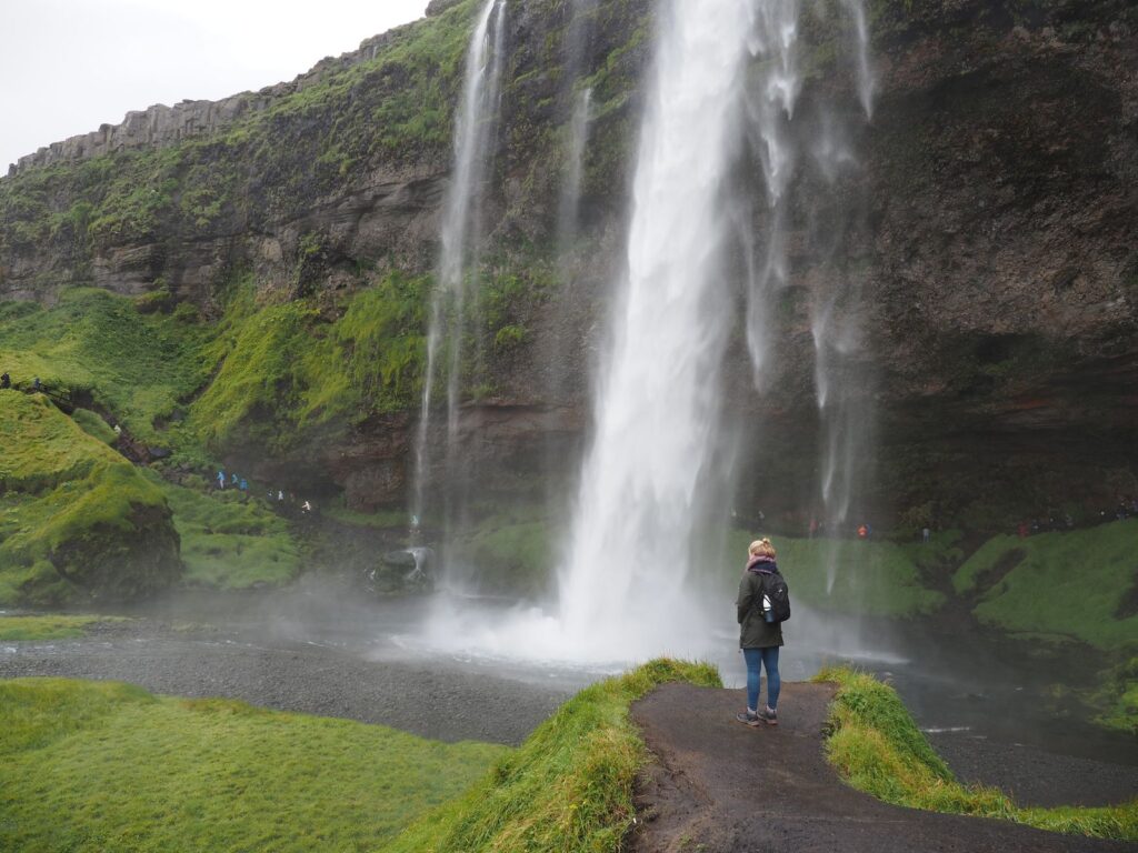 Vrouw staat op uitkijkpunt voor Seljalandsfoss waterval op IJsland