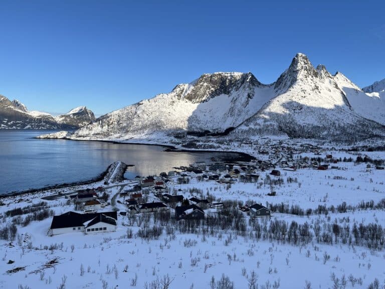 Zicht vanaf een heuvel over een besneeuwde Mefjord Brygge en het dorp eromheen