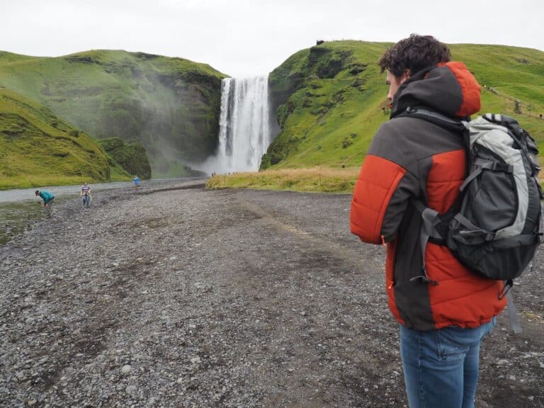 Man staat voor Skogafoss waterval op IJsland