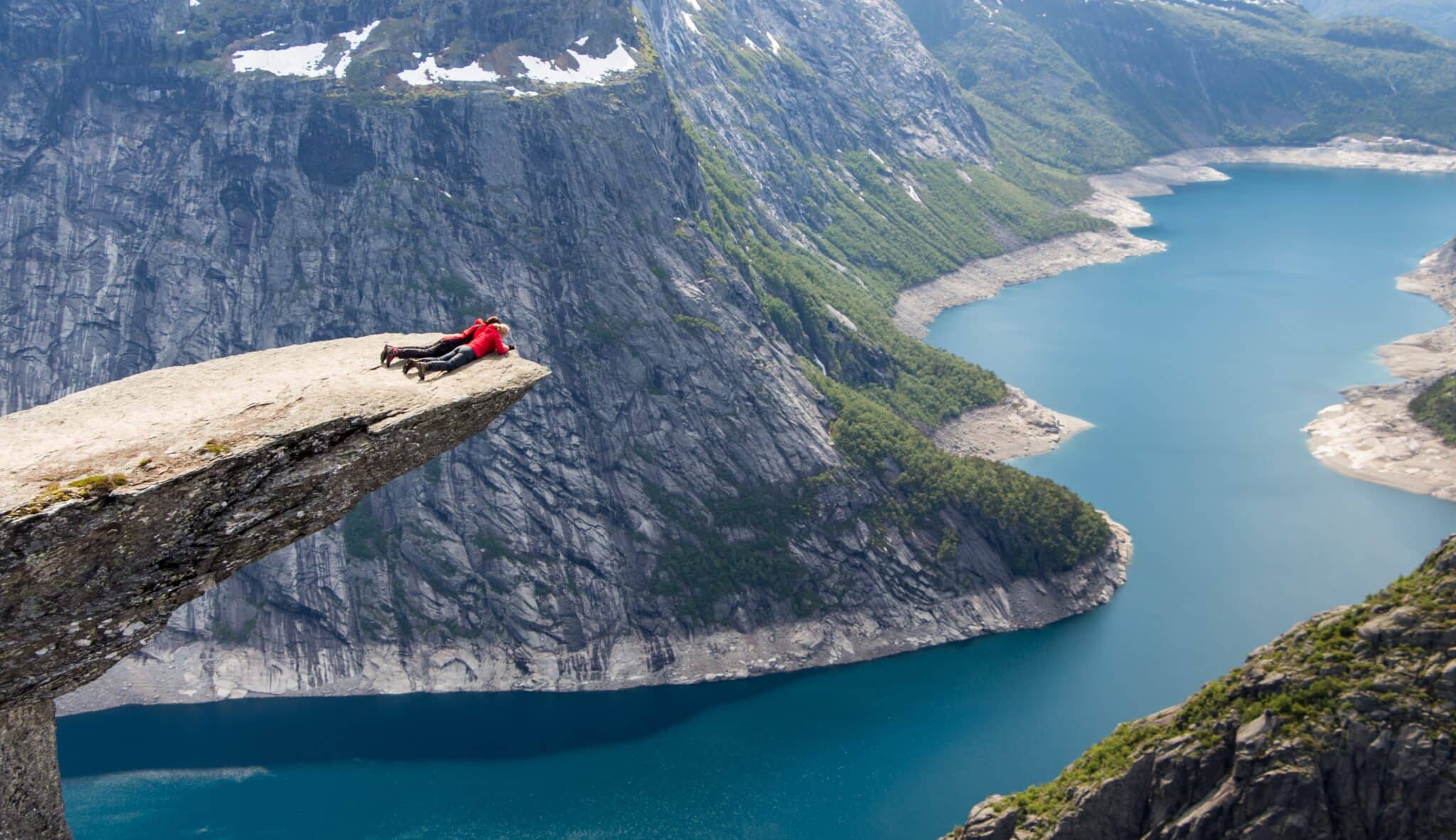 Mensen kijken liggend over de rand van de Trolltunga in Noorwegen