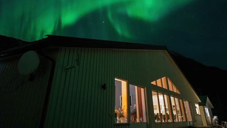 Buitenkant van het gebouw van Arctic Panorama Lodge, met noorderlicht erboven