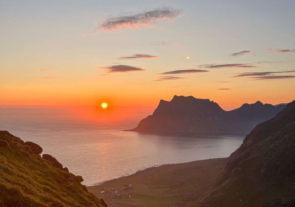 Zicht op de middernachtzon boven het water, vanaf een berg op de Lofoten