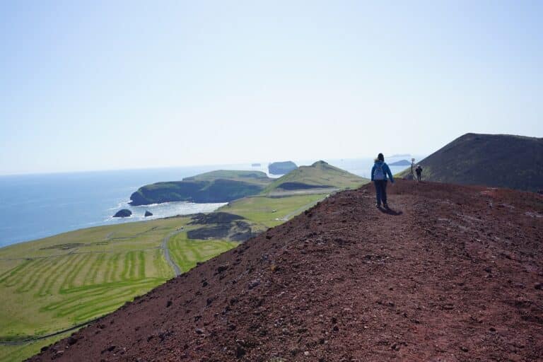 Wamdelaar loopt over Eldfell vulkaan op IJsland, uitzicht op zee