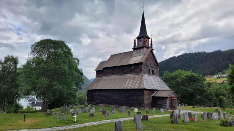 Houten staafkerk in Kaupanger, met aantal graven eromheen.