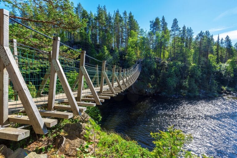 Houten brug over rivier in Finland, met bossen op de achtergrond