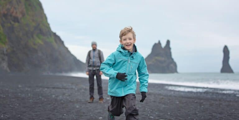 Jongetje rent op strand bij Reynisdrangar IJsland