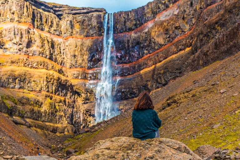 Meisje bij Hengifoss waterval in de buurt van Egilsstadir, IJsland