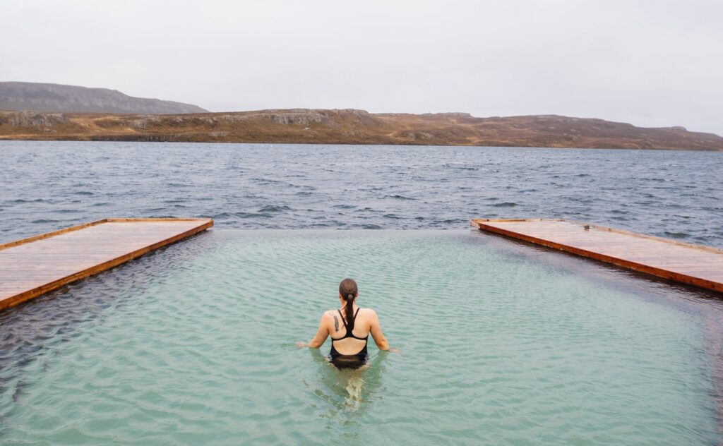 Vrouw kijkt uit over het water bij Vök Baths, Egilstadir, IJsland
