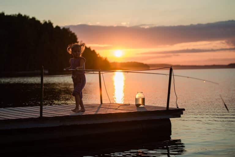 Jong meisje met hengel bij een Fins meer tijdens de middernachtzon