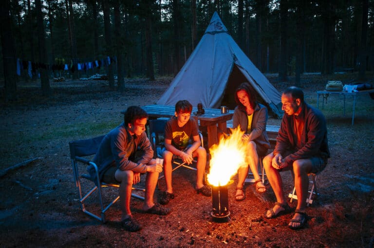 Familie bij kampvuur voor tent in Noorwegen.