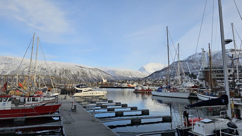 De haven van Tromsø: steiger en boten met besneeuwde bergen op de achtergond