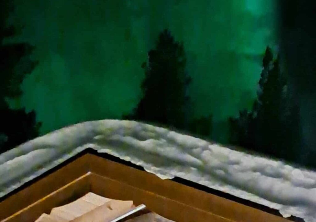 Noorderlicht boven een besneeuwd dak in Lapland