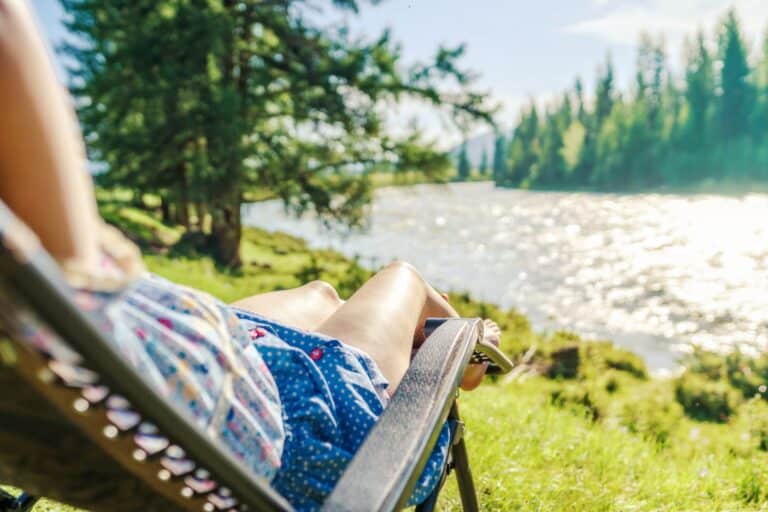 Vrouw in stoel in de zon aan rivier in Zweden