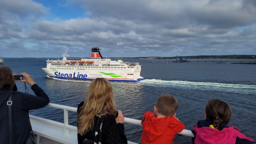 Mensen kijken vanaf de boot naar een voorbijvarende ferry.
