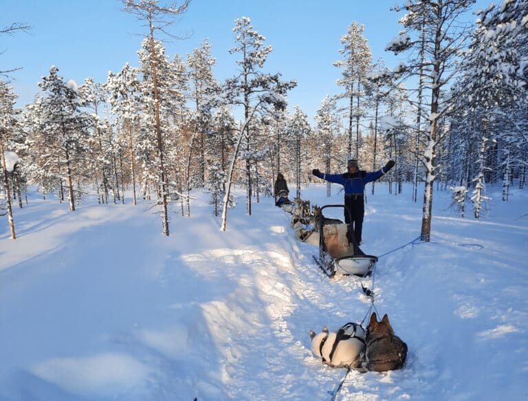 Man staat naast slede tijdens rustpauze husky safari