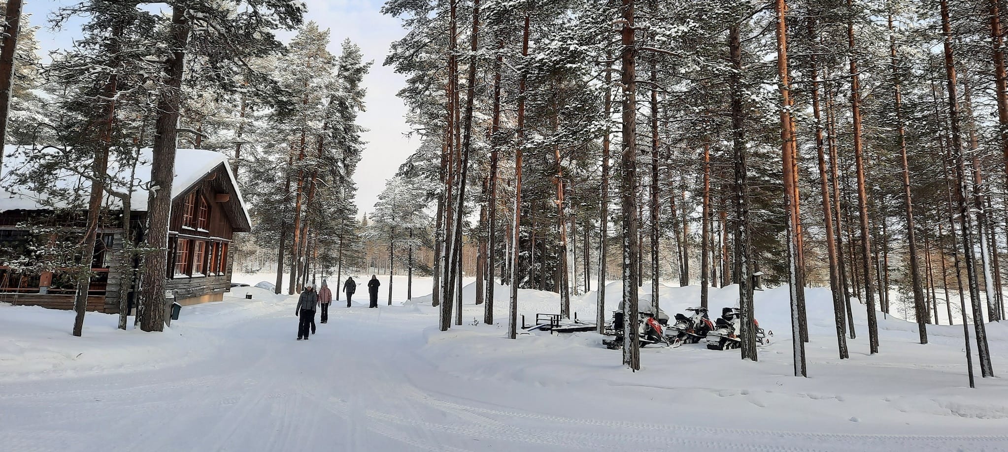 Mensen lopen over besneeuwd pad bij hoofdgebouw Himmerki Lodge, Lapland