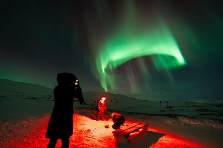 Vrouw fotografeert het noorderlicht met haar mobiele telefoon in Lapland.