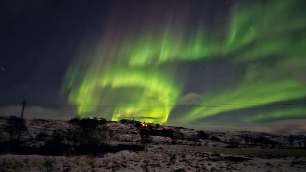 Noorderlicht boven besneeuwde heuvel in Noord-Noorwegen.