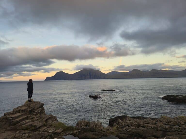 Vrouw kijkt uit over baai Faeröer eilanden