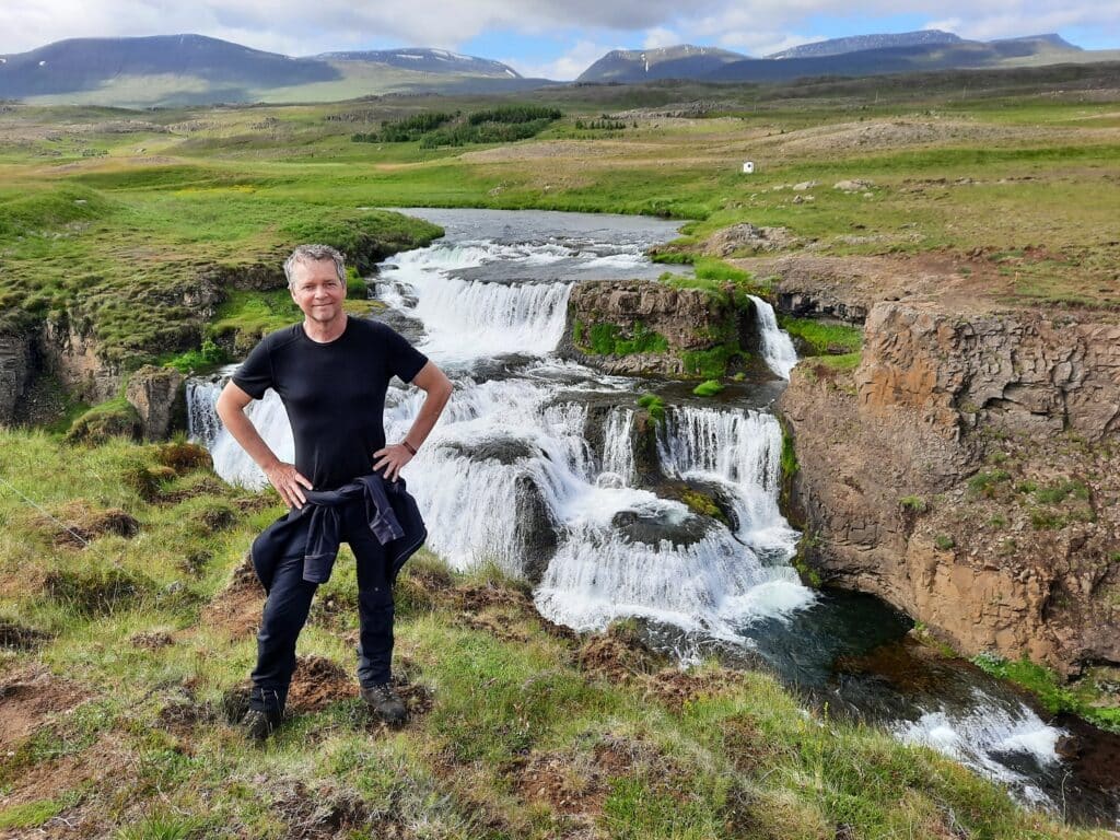 Man poseert voor Reykjafoss waterval op IJsland