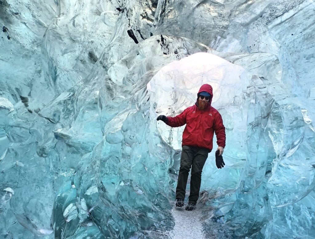 Man met rode jas in ijsgrot op IJsland