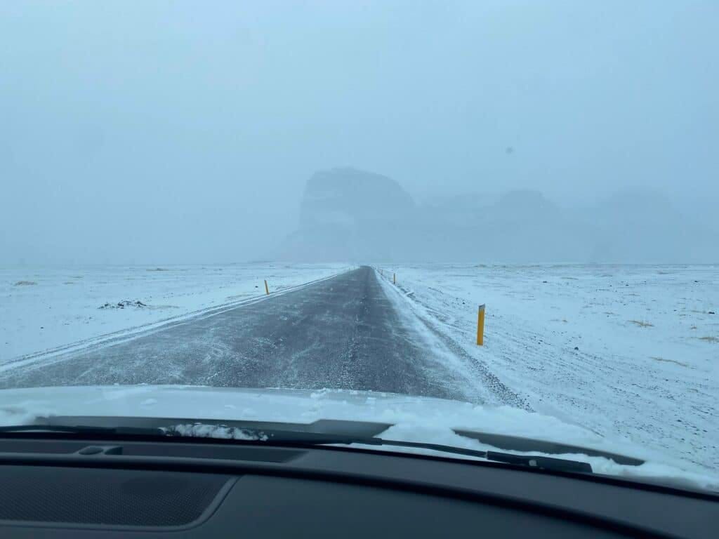 Auto rijdt over weg op IJsland door winters landschap.
