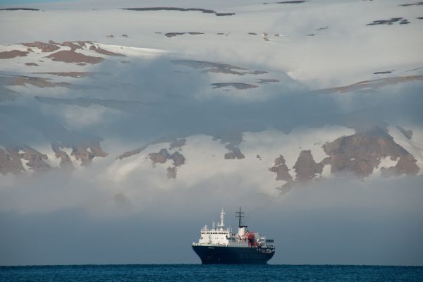 Expeditie schip bij Spitsbergen met besneeuwde bergen op de achtergrond