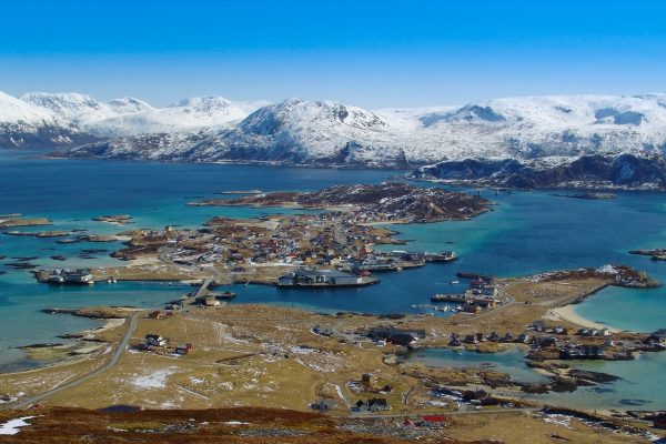 Het eiland Sommaroy omringd met azuurblauw water en besneeuwde bergtoppen