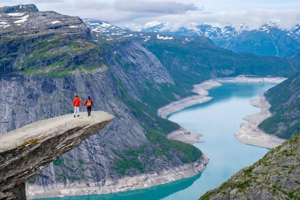 Twee reizigers op de rots Trollrunga, met uitzicht over het fjord