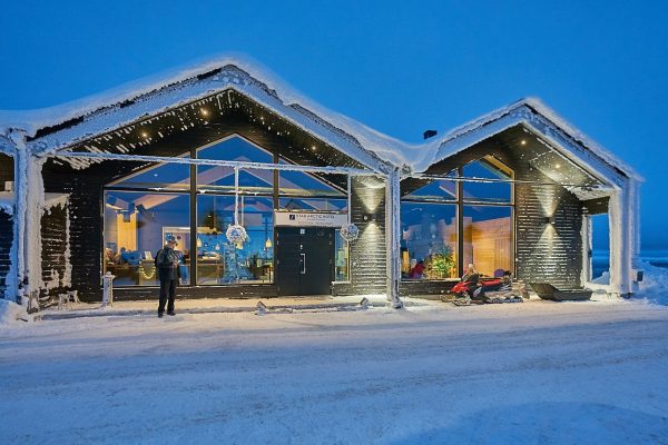 Buitenkant van de ingang Star Arctic hotel met sneeuwscooter naast de deur