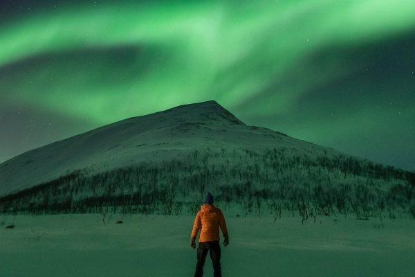 Man uitkijkend over berg in Noorwegen met noorderlicht