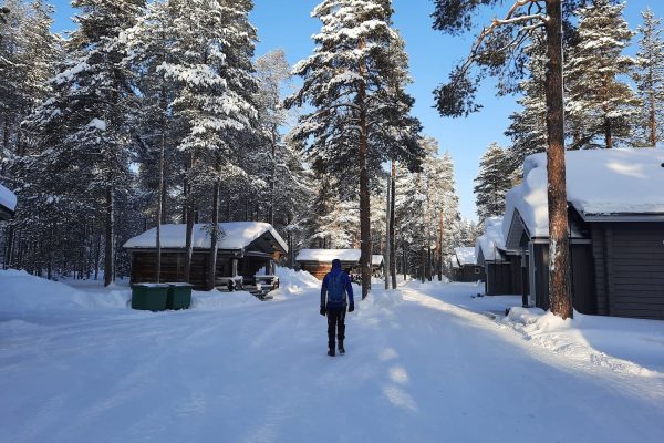 Man wandelt over besneeuwd pad bij Himmerki Lodge, Fins Lapland