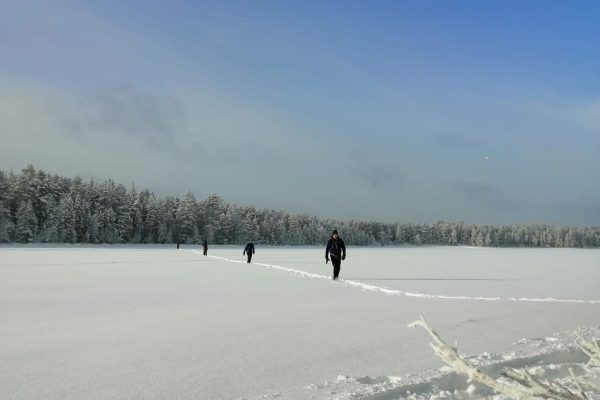 Mensen wandelen over besneeuwd meer in Fins Lapland