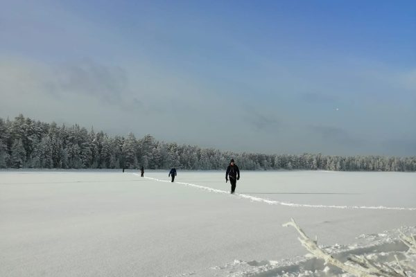 Mensen wandelen over besneeuwd meer in Fins Lapland