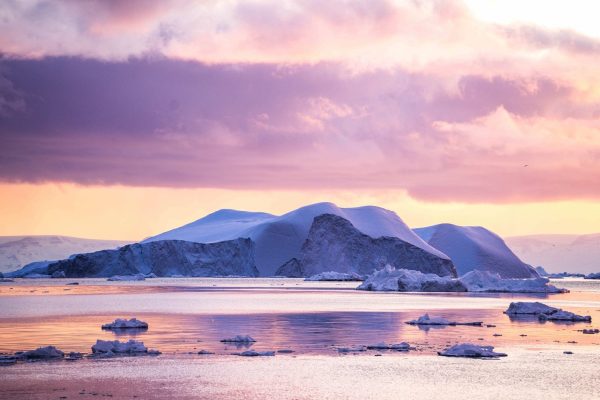 IJsfjord Ilulissat, Groenland met een roze lucht boven een ijsberg.