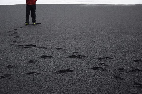 Voetstappen in het zwarte zand bij Reynisfjara Black Sand Beach, Vik, IJsland