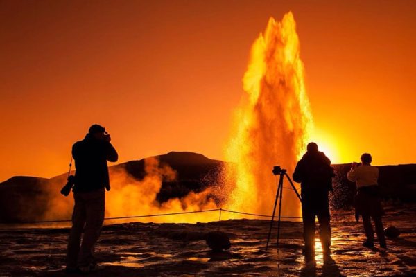 Fotografen maken foto's van spuitende geiser bij zonsondergang bij Strokkur Geysir op IJsland