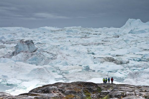 Mensen kijken uit over ijsbergen bij Ilulissat in Groenland