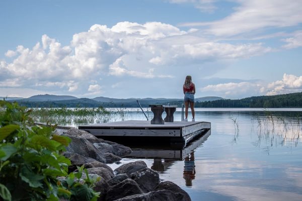 Vrouw kijkt uit over meer in Zweden vanaf een steiger