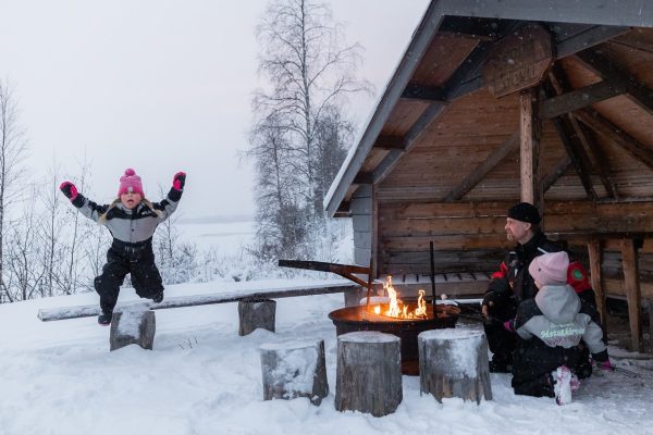Kind springt in de lucht bij kampvuur in Fins Lapland