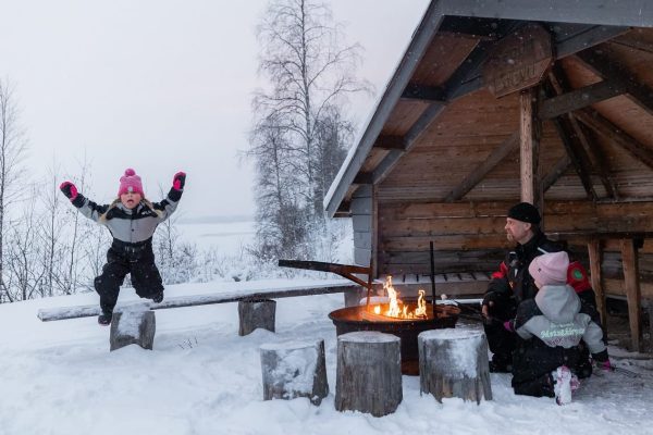 Kind springt in de lucht bij kampvuur in Fins Lapland