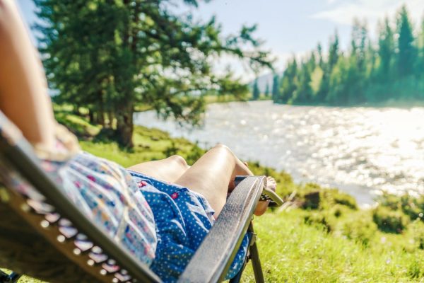 Vrouw in stoel in de zon aan rivier in Zweden